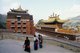 China: Tibetan pilgrims pass the Grand Gold Tile Temple Hall, Labrang Monastery, Xiahe, Gansu province